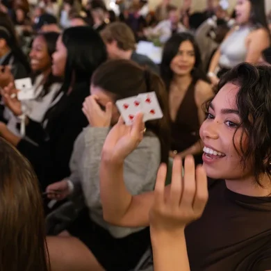 Audience members holding playing cards and smiling during Anna DeGuzman's live magic show