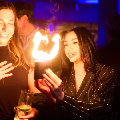 Anna DeGuzman performing close-up magic with fire for an amazed spectator