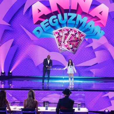 Anna DeGuzman performing magic on stage with Terry Crews before judges
